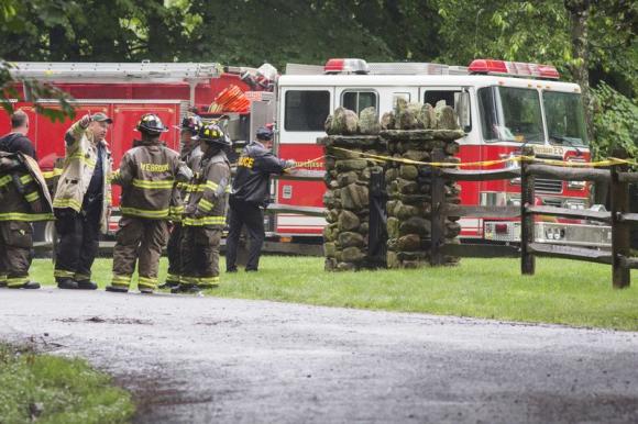 Police and firefighters stand near the site of a small plane crash in the town of Harrison, Westchester County, New York